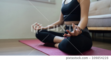 Young Asian woman meditating with trainer online on laptop at home Young Asian woman meditating with trainer online on laptop at home 109854228