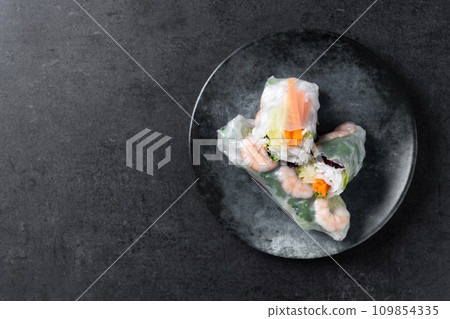 Vietnamese spring rolls with vegetables, rice noodles and prawns on black slate background Vietnamese spring rolls with vegetables, rice noodles and prawns on black slate background 109854335