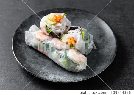 Vietnamese spring rolls with vegetables, rice noodles and prawns on black slate background Vietnamese spring rolls with vegetables, rice noodles and prawns on black slate background 109854336