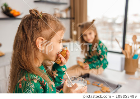 Two kids looking busy while cooking cookies in the kitchen Two kids looking busy while cooking cookies in the kitchen 109855499