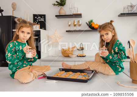 Two kids looking busy while cooking cookies in the kitchen Two kids looking busy while cooking cookies in the kitchen 109855506