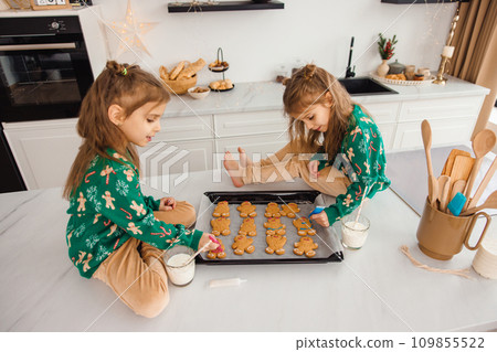 Long-haired cute kid sitting on the table and preparing ginger cookies 109855522