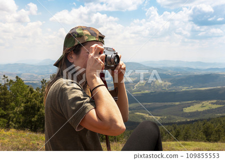 Tourist girl photographing with vintage photo camera at the top of the mountain peak 109855553