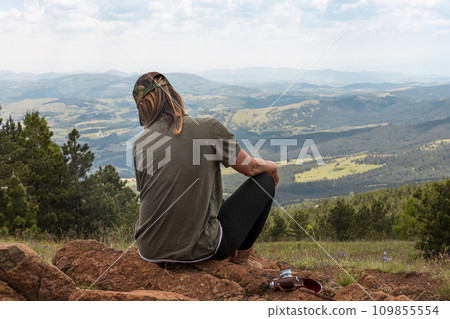 Tourist girl hiker, photographer resting at the top of the mountain and enjoying amazing landscape view of mountains and beautiful sky Tourist girl hiker, photographer resting at the top of the mountain and enjoying amazing landscape view of mountains and beautiful sky 109855554