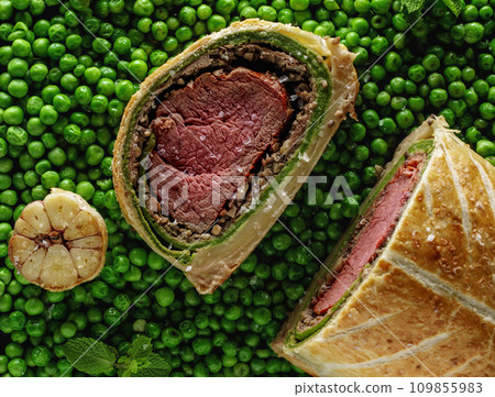 Homemade Christmas Beef Wellington as advent creation on green pees background. Food plating and aesthetic concept 109855983