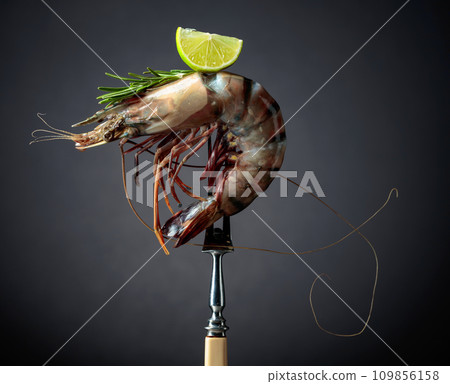 Fresh tiger prawn with rosemary and lime slice on a black background. Fresh tiger prawn with rosemary and lime slice on a black background. 109856158