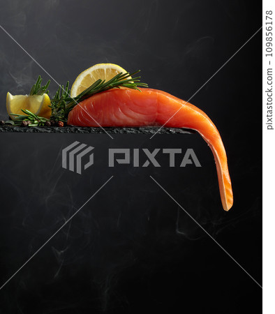 Smocked salmon with rosemary, lemon, and peppercorn on a black background. Smocked salmon with rosemary, lemon, and peppercorn on a black background. 109856178