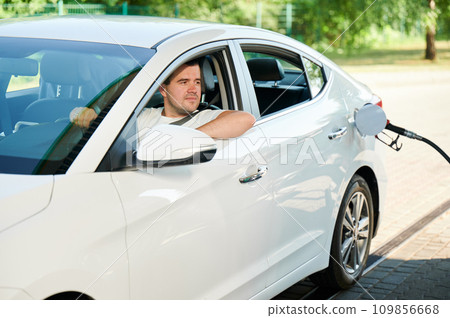 Man waiting for his car will be refueled. Confident man looking through window of auto if tank is filled. 109856668