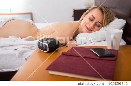 The girl sleeps uncovered on the bed 109856841