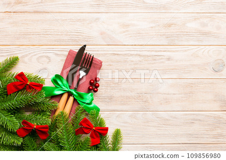 Top view of christmas decorations on wooden background. Fork and knife on napkin tied up with ribbon and empty space for your design. New year pattern concept 109856980