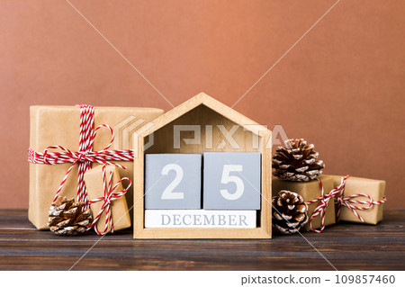 25 december. Christmas composition on colored background with a wooden calendar, with a gift box, toys, bauble copy space 109857460
