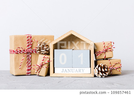 1 january. Christmas composition on colored background with a wooden calendar, with a gift box, toys, bauble copy space 109857461