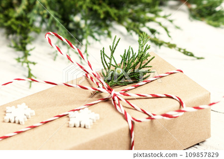 Christmas gift or present box wrapped in kraft paper with decoration on rustic wooden background. Toned 109857829