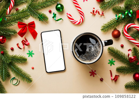 top view of smart phone with hot cup of coffee. Christmas decoration on colored background 109858122