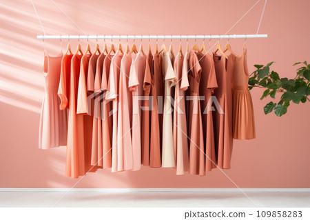 Warm knitted, autumn, winter clothes hanging on a rack, Peach Fuzz color of the year 109858283