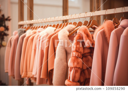 Warm knitted, autumn, winter clothes hanging on a rack, Peach Fuzz color of the year Warm knitted, autumn, winter clothes hanging on a rack, Peach Fuzz color of the year 109858290