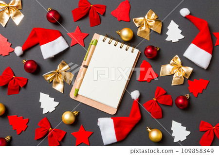 Top view of notebook on black background with New Year toys and decorations. Christmas time concept Top view of notebook on black background with New Year toys and decorations. Christmas time concept 109858349