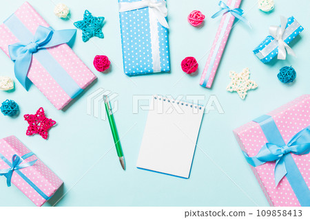 Top view of notebook on blue background made of Christmas decorations. New Year time concept Top view of notebook on blue background made of Christmas decorations. New Year time concept 109858413