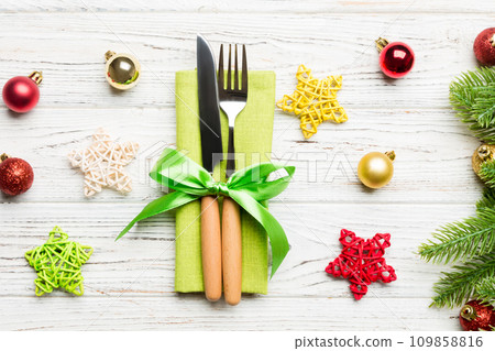 Top view of festive cutlery on new year wooden background. Close up of christmas decorations. Holiday dinner concept Top view of festive cutlery on new year wooden background. Close up of christmas decorations. Holiday dinner concept 109858816