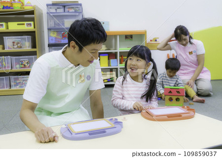 A girl and a male nursery teacher drawing at a nursery school. Photography cooperation: Ariake College of Education and Art A girl and a male nursery teacher drawing at a nursery school. Photography cooperation: Ariake College of Education and Art 109859037