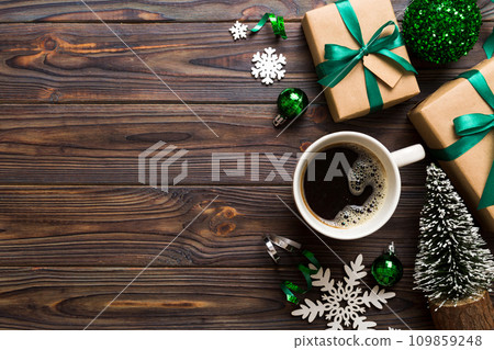 Delicious fresh festive morning coffee in a ceramic cup with little wrapped gifts, ornament and xmas toy. Cup of coffee and new year toys 109859248