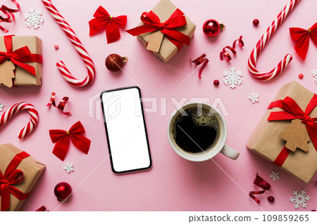 top view of smart phone with hot cup of coffee. Christmas decoration on colored background top view of smart phone with hot cup of coffee. Christmas decoration on colored background 109859265