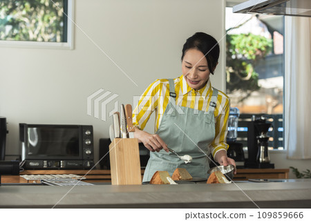 A woman putting fresh cream on a chiffon cake A woman putting fresh cream on a chiffon cake 109859666