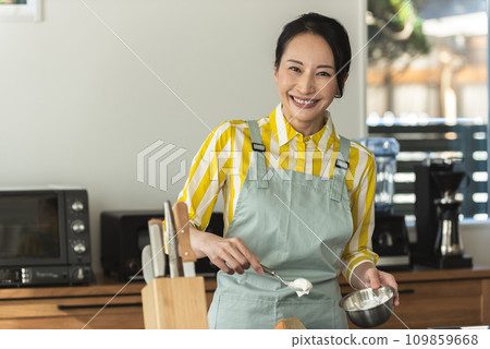 A woman putting fresh cream on a chiffon cake A woman putting fresh cream on a chiffon cake 109859668