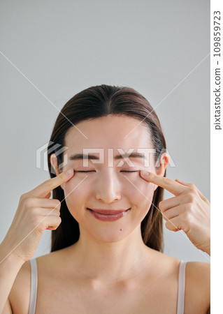 A woman in her 30s putting her finger on her eyes A woman in her 30s putting her finger on her eyes 109859723