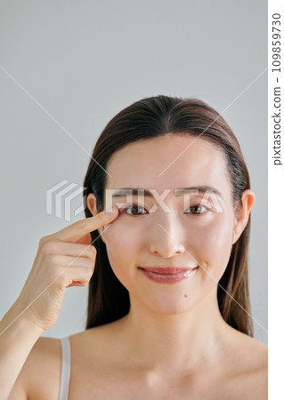 一名 30 多歲的女性將手指放在右眼上 一名 30 多歲的女性將手指放在右眼上 109859730