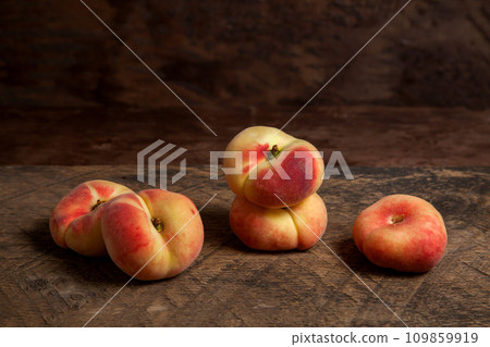 Several saturn peaches or flat peaches on wooden background.. 109859919