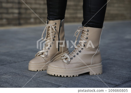 Woman in leather boots and jeans outdoors. Close up of female legs in fashion footwear 109860805