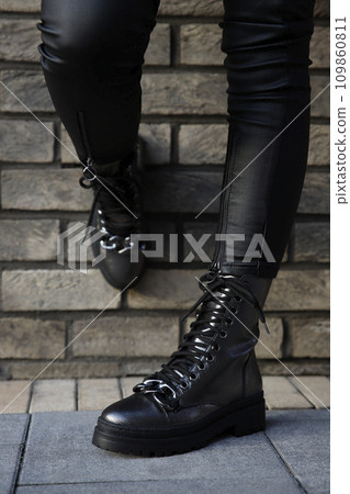 Woman in leather black boots and jeans outdoors. Close up of female legs in fashion footwear 109860811