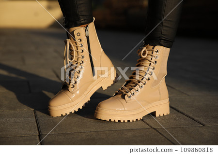 Woman in stylish leather boots and jeans outdoors. Close up of female legs in fashion footwear 109860818