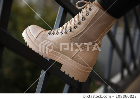 Woman in stylish leather boots and jeans outdoors. Close up of female legs in fashion footwear 109860822