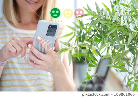 Woman pressing smiley face on mobile phone closeup. Customer evaluation concept Woman pressing smiley face on mobile phone closeup. Customer evaluation concept 109861066