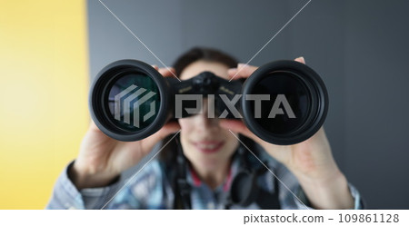 Young woman looking through black professional binoculars closeup 109861128