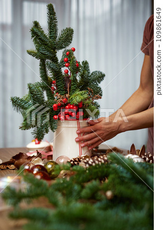 Woman making Christmas arrangement with fir branches. craft handmade decor. 109861649