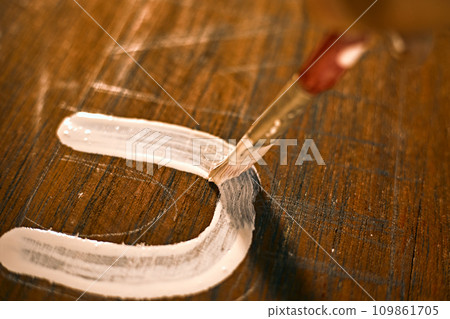 Painted wooden surface with brush and white paint. Painted wooden surface with brush and white paint. 109861705