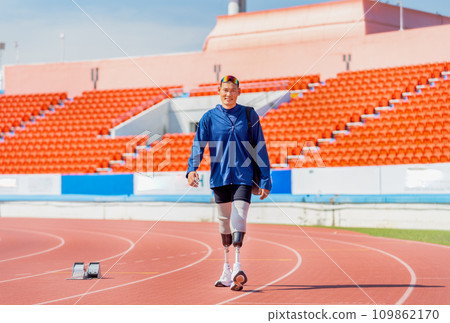 Sport man athlete prosthesis legs carry the bag and walk on the track of the stadium with day light and happiness. Sport man athlete prosthesis legs carry the bag and walk on the track of the stadium with day light and happiness. 109862170