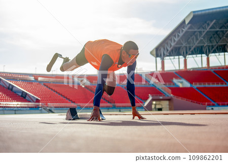 Sport man athlete with a prosthesis on his leg lie down and action of stretch one leg back and up also look forward to warm up before exercise at the stadium. Sport man athlete with a prosthesis on his leg lie down and action of stretch one leg back and up also look forward to warm up before exercise at the stadium. 109862201
