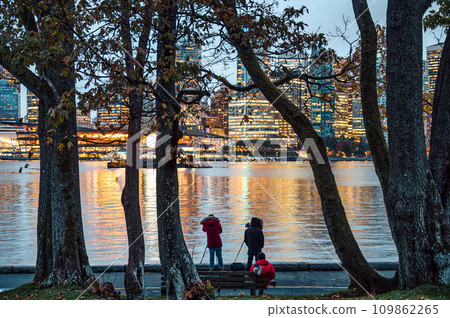 Group of tourist taking a photo with cityscape of building from Stanley Park in the evening Group of tourist taking a photo with cityscape of building from Stanley Park in the evening 109862265