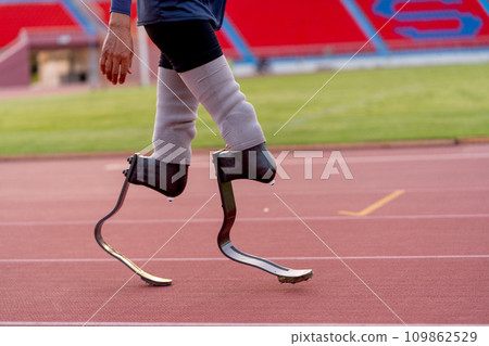 Side view of sport man athlete prosthesis legs stand and warm up legs on track in the stadium. Side view of sport man athlete prosthesis legs stand and warm up legs on track in the stadium. 109862529