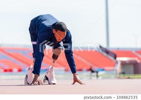 Front side view of sport man athlete with a prosthesis on his leg action of start to run on the track at the stadium. Sport concept. 109862535