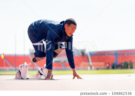 Side view of sport man athlete with a prosthesis on his leg action of start to run on the track at the stadium. Sport concept. 109862536