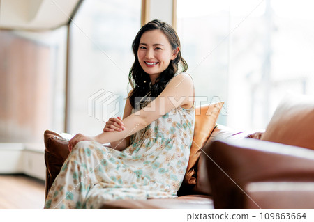 一個女人坐在沙發上和放鬆 一個女人坐在沙發上和放鬆 109863664