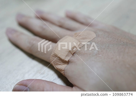 將創可貼放在男人的手背上。 將創可貼放在男人的手背上。 109863774