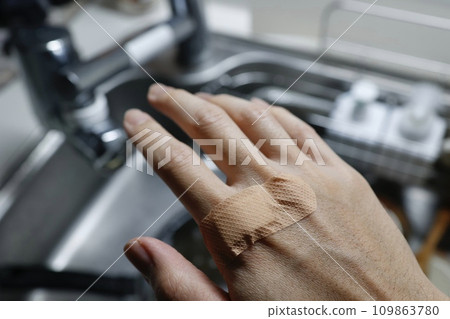A bandaid is placed on the back of a man's hand. A bandaid is placed on the back of a man's hand. 109863780