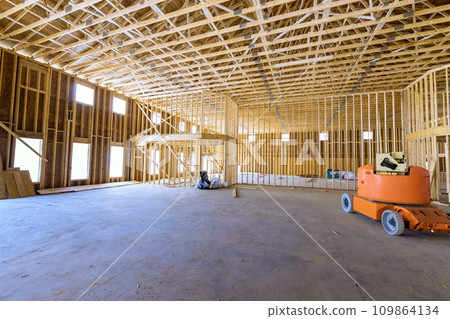 Wooden beams framework construction is under way for construction of new house 109864134