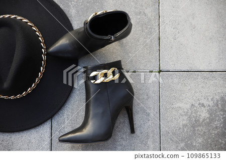 Stylish black leather boots and hat outdoors in the street 109865133